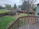 View from the deck of a grass backyard, featuring mature trees, perimeter fencing, and a mulch-covered area at 880 Orion Dr, Lafayette, CO 80026