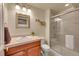 Bathroom featuring cherry vanity, framed mirror, step-in shower with glass door, and neutral finishes at 9784 S Iris Ct, Littleton, CO 80127