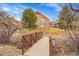 Exterior of home with bridge in foreground, featuring lush landscaping and mature trees at 9784 S Iris Ct, Littleton, CO 80127