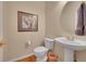 Powder room featuring a pedestal sink, round mirror, decorative picture and wood floors at 9784 S Iris Ct, Littleton, CO 80127