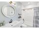 Bright bathroom featuring a round mirror, modern vanity, and bathtub with shower at 1164 S High St, Denver, CO 80210