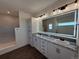 Bathroom with double sinks, granite countertop, shaker cabinets, large illuminated mirror, and walk in shower at 59440 E 56Th Ave, Strasburg, CO 80136