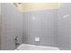 Close-up of the tub and shower featuring gray tile surround and chrome shower fixture at 9814 Norfolk St, Commerce City, CO 80022