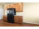 Modern kitchen featuring wood cabinets, light countertops, black appliances, and hardwood floors at 9814 Norfolk St, Commerce City, CO 80022