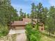 Aerial shot of a home nestled among tall pine trees, highlighting its expansive driveway and roof at 171 Columbine St, Larkspur, CO 80118