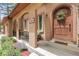 Inviting front porch features a lovely arched doorway, beautiful landscaping, and a cozy seating area at 171 Columbine St, Larkspur, CO 80118