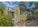 Charming yellow home featuring a white picket fence, siding, and black shuttered windows, nestled under a bright blue sky at 1665 S Madison St, Denver, CO 80210