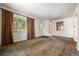 Bright and airy living room featuring neutral walls, carpet, and a window with brown curtains, leading to a front door at 1665 S Madison St, Denver, CO 80210