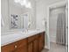 Bathroom with wood cabinets, white countertop, modern fixtures, and a shower-tub combo behind a stylish curtain at 5511 Wabash St, Denver, CO 80238
