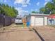 Exterior view of a detached garage and fence, with a car parked nearby on a dirt and gravel drive at 4112 S Galapago St, Englewood, CO 80110