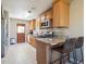 Well-lit kitchen with stainless steel appliances, tile floors, and a breakfast bar area at 4112 S Galapago St, Englewood, CO 80110