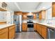 Well-lit kitchen featuring stainless steel appliances, wood cabinetry, and tile backsplash at 4604 Routt St, Wheat Ridge, CO 80033