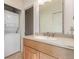 Bathroom features laundry closet, vanity with a light wood finish, and a large sliding mirror at 7318 W Cedar Cir, Lakewood, CO 80226