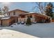 A charming two-story home has a two-car garage and a cozy, snow-covered landscaped front yard at 7318 W Cedar Cir, Lakewood, CO 80226