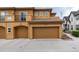 Exterior shot of the townhome with two garage doors, and neutral paint with tile roof at 7777 E 23Rd Ave # 201, Denver, CO 80238