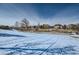 Expansive snowy field with tire tracks, framed by bare trees and houses in the background at 4143 Da Vinci Dr, Longmont, CO 80503