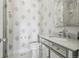 Chic powder room with elegant patterned wallpaper, modern fixtures, and stylish vanity, blending luxury with functionality at 423 N Snowmass Cir, Superior, CO 80027