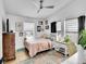 Cozy bedroom features a ceiling fan, multiple windows, a pink comforter and stylish décor at 2143 S Acoma St, Denver, CO 80223