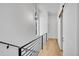 Modern hallway with hardwood floors, black metal railing, and a contemporary light fixture at 2143 S Acoma St, Denver, CO 80223