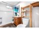 Bathroom with tiled shower, vanity, and natural wood open shelving storage next to the toilet at 2698 Fern Dr, Westminster, CO 80030