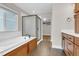 Bright bathroom features soaking tub with shower, wood cabinets and tile flooring at 6334 Empire Ave, Frederick, CO 80516