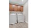 Laundry room features tile floors and wood cabinets above washer and dryer at 6334 Empire Ave, Frederick, CO 80516