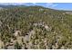 Expansive aerial view of a secluded home embraced by dense woodlands, offering privacy and natural beauty at 11421 Belle Meade Dr, Conifer, CO 80433