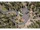 Stunning aerial view of a luxury home nestled within a dense forest, complete with a winding driveway and manicured landscaping at 11421 Belle Meade Dr, Conifer, CO 80433