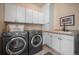 Modern laundry room with front-loading washer/dryer and white cabinets for ample storage at 11421 Belle Meade Dr, Conifer, CO 80433