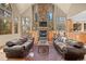 Bright living room featuring a stone fireplace, high ceilings, and natural light from large windows at 11421 Belle Meade Dr, Conifer, CO 80433