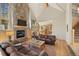 Open living room with stone fireplace and wood floors offering a view into the kitchen at 11421 Belle Meade Dr, Conifer, CO 80433