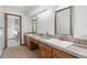 Bright bathroom featuring double sinks with tile countertop and a doorway leading to a tiled shower at 10101 W 72Nd Ave, Arvada, CO 80005