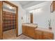 Bathroom with wooden vanity featuring light tile countertops and a shower with patterned curtain at 10101 W 72Nd Ave, Arvada, CO 80005