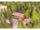 An aerial view reveals a two-story home with a brown roof, complementing the dense evergreen surroundings at 11457 Nancys Dr, Conifer, CO 80433