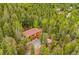 Aerial view of a mountain home nestled among evergreen trees with a driveway and detached garage at 11457 Nancys Dr, Conifer, CO 80433