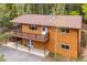 Aerial view of a two story home with a deck, wood siding, and a surrounding forest at 11457 Nancys Dr, Conifer, CO 80433