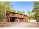 Charming multi-level home featuring a covered deck, wood siding, and a detached garage at 11457 Nancys Dr, Conifer, CO 80433