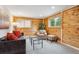Comfortable living room with wood paneling, a plush sofa with red pillows, and a cozy patterned armchair at 11457 Nancys Dr, Conifer, CO 80433