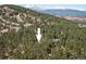 Expansive aerial view of a mountain home nestled among lush green trees with snow-capped mountain range in the background at 31948 Highway 72, Golden, CO 80403