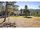 Exterior view of a rustic home surrounded by tall trees, a gravel driveway, and mountain views at 31948 Highway 72, Golden, CO 80403