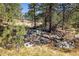 Scenic landscape with rocky terrain, lush trees and a glimpse of a home in the background at 31948 Highway 72, Golden, CO 80403