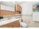 Cozy bathroom with a sink, toilet, and wooden cabinets and trim at 12097 E Mexico Ave, Aurora, CO 80012