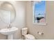 Stylish half bathroom with pedestal sink, oval mirror, and window at 5654 N Emporia St, Denver, CO 80238