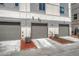 Three garages with neutral doors accented by tasteful landscaping and modern exterior at 5654 N Emporia St, Denver, CO 80238