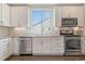 Modern kitchen features stainless steel appliances, white cabinetry, and tile backsplash at 5654 N Emporia St, Denver, CO 80238