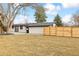 Backyard featuring a grass lawn surrounded by wood fence, trees, and a patio at 2505 Upham St, Lakewood, CO 80214
