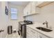 Well-equipped laundry room featuring a modern washer and dryer, ample countertop space, and overhead cabinets for storage at 7258 Oasis Dr, Castle Rock, CO 80108