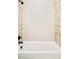 A white bathtub with chrome fixtures and light neutral patterned tile at 2773 S Garfield St, Denver, CO 80210