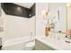 Modern bathroom features black and white tiled shower over tub, sink with gold mirror and sconces at 2773 S Garfield St, Denver, CO 80210