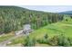 Aerial view of a mountain home with mature trees, landscaping, and exterior deck at 7614 Malamute Dr, Evergreen, CO 80439